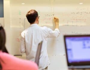 A man answering technical interview questions at a whiteboard