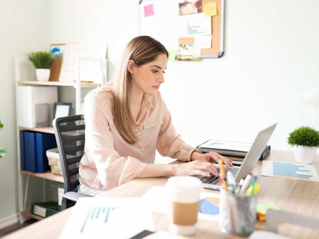 woman sitting at desk typing an email on a laptop