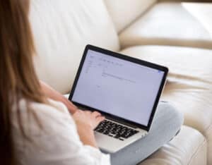 student sitting on couch with laptop open to half-written cover letter