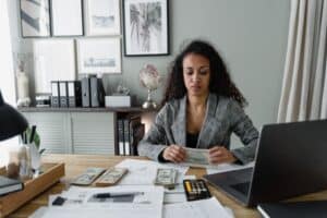 employee holding money while looking at calculator for forensic accounting job