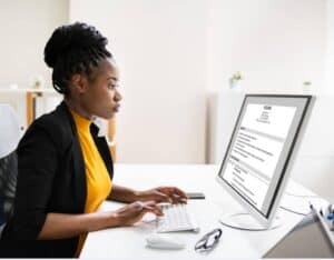 woman sitting at computer typing and working on resume