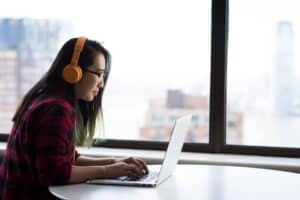 woman typing on laptop with headphones on