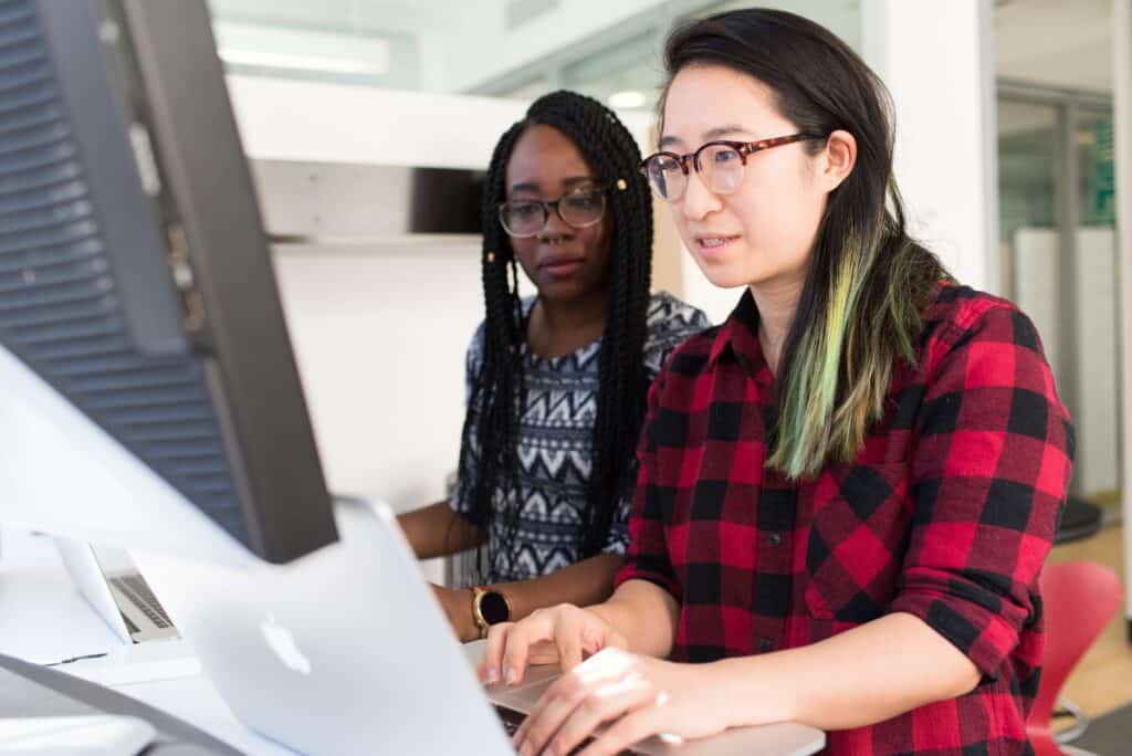 two software engineers sitting and looking at a computer