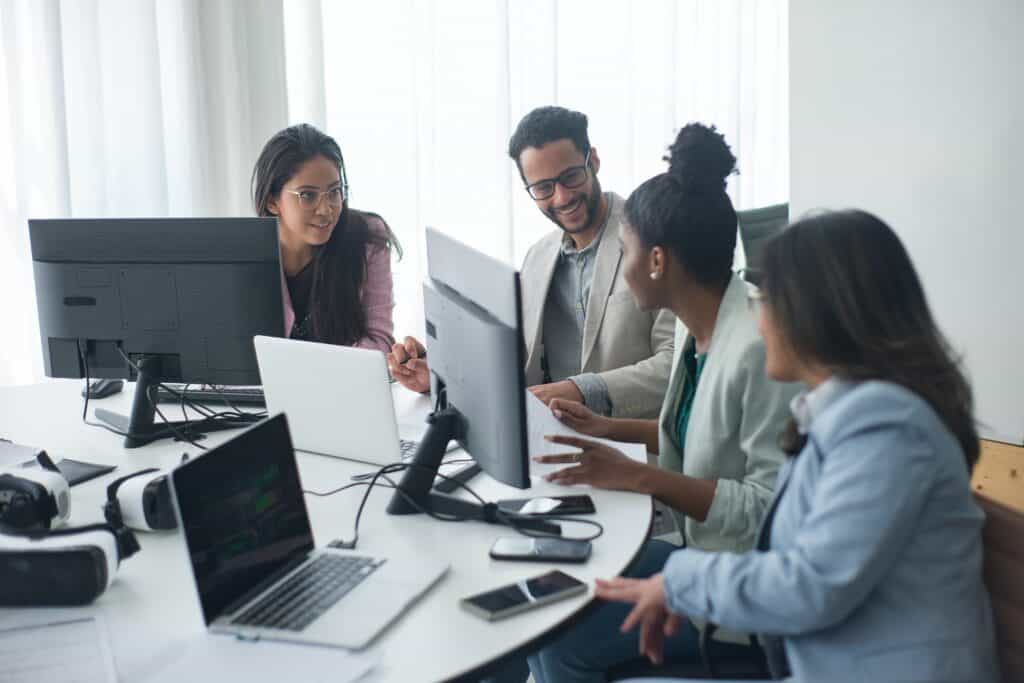 Team working together in an office with computers on the table.