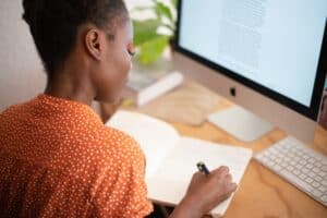 person using writing skills at work by writing in a notebook