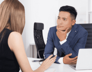 Asian man listening to woman answer tell me about yourself interview question